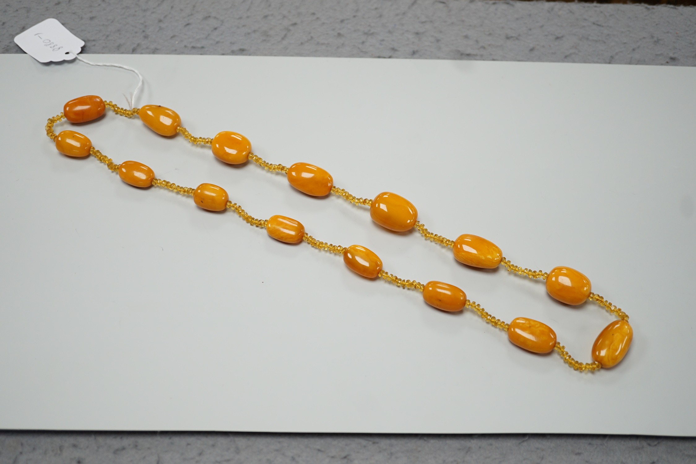 A single strand graduated fifteen amber bead necklace, with multiple amber? spacers, 84cm, gross weight 89 grams.